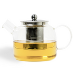 Clear glass teapot with metal infuser and handle, filled with tea, on a white background.