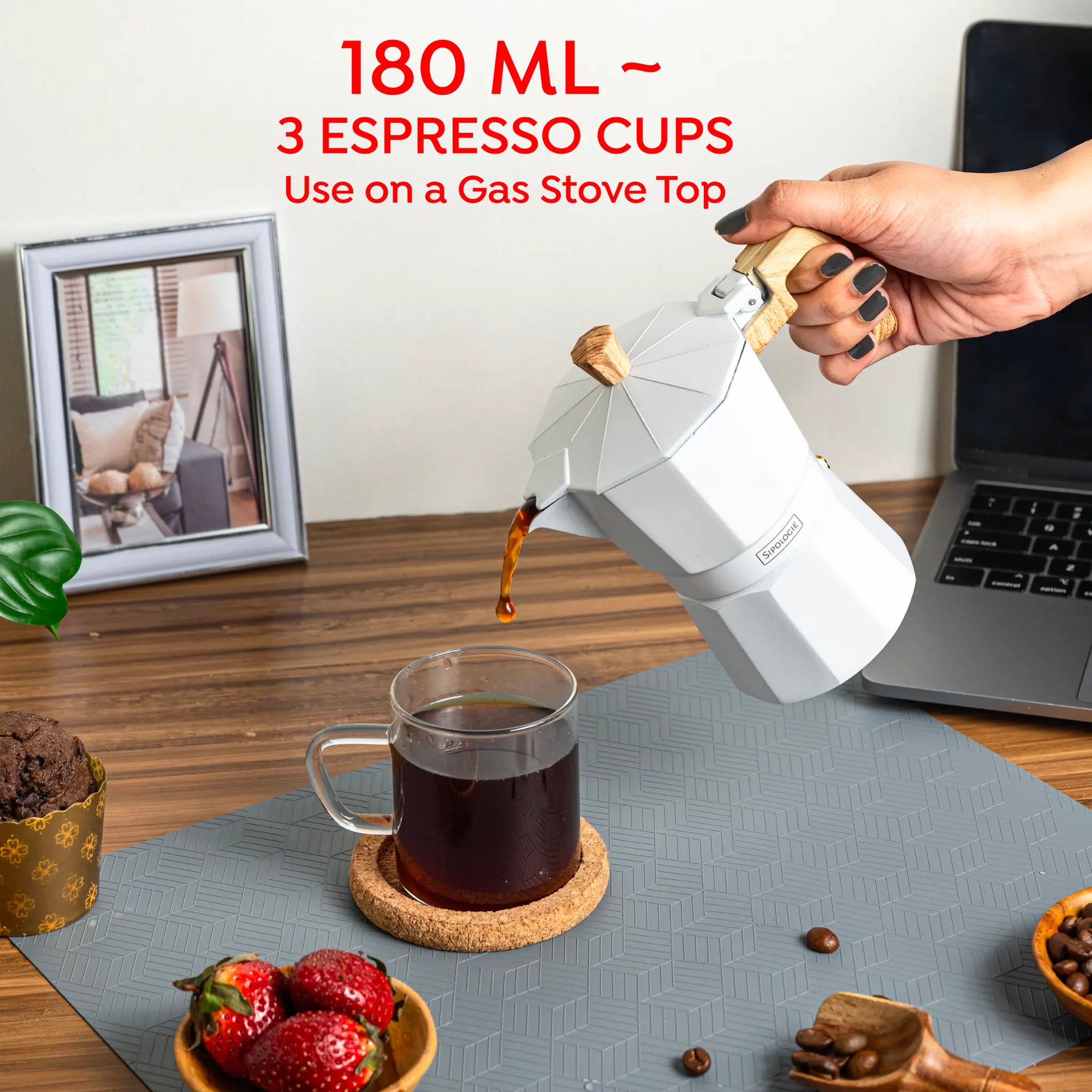 A white stovetop moka pot being poured with coffee into a clear glass mug on a gray mat, with a hand holding the handle. Red text at the top reads '180 ML ~ 3 ESPRESSO CUPS Use on a Gas Stove Top'.