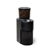 A black coffee grinder with a clear bean hopper filled with coffee beans, shown on a solid white background.