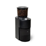 A black coffee grinder with a clear bean hopper filled with coffee beans, shown on a solid white background.