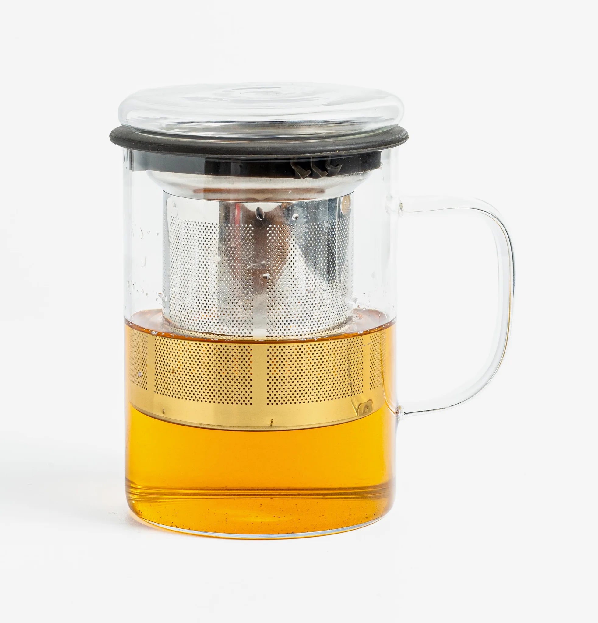A clear glass teapot with a handle, a metal infuser, and a black lid, filled with amber tea, shown on a light gray background.