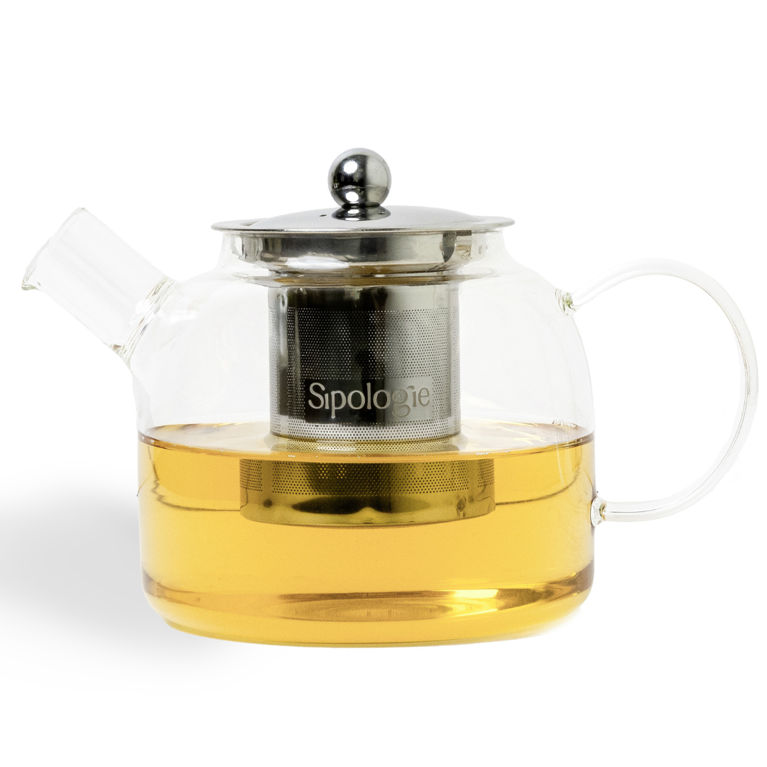 Clear glass teapot with metal infuser and handle, filled with tea, on a white background.